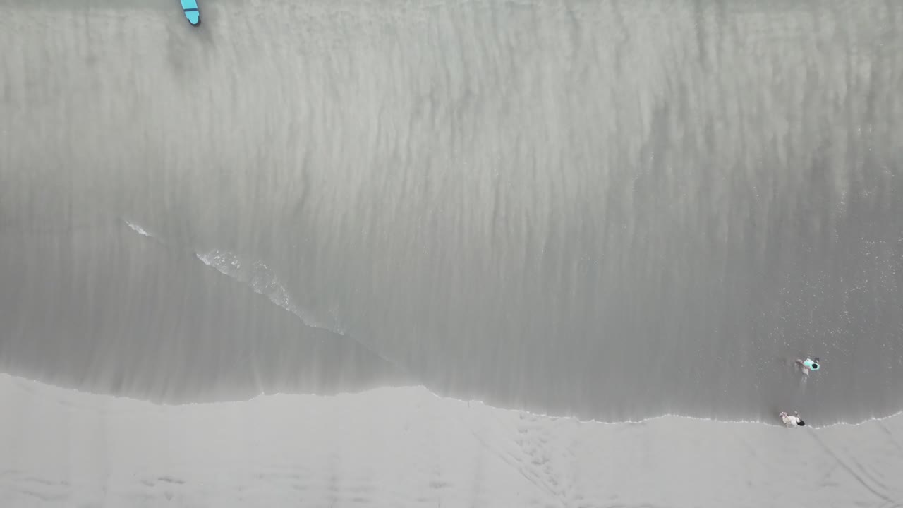 Aerial View of Beach with People and Surfboard