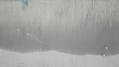 aerial view of beach with people and surfboard