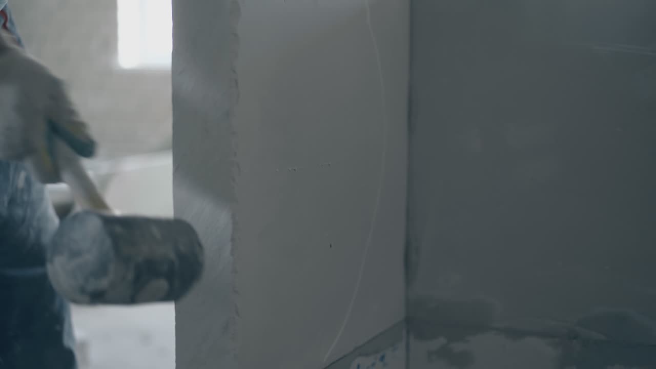 man holds large rubber hammer and aligns plasterboard