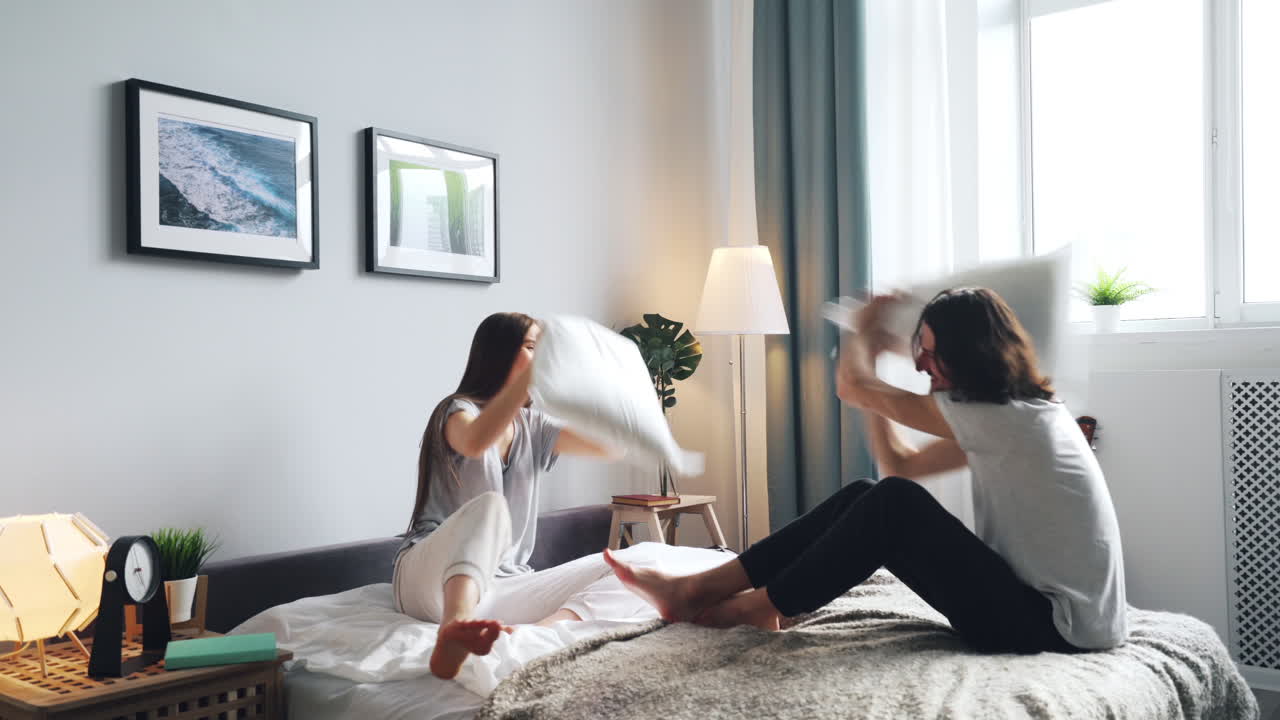 Couple having a fun pillow fight in their bedroom