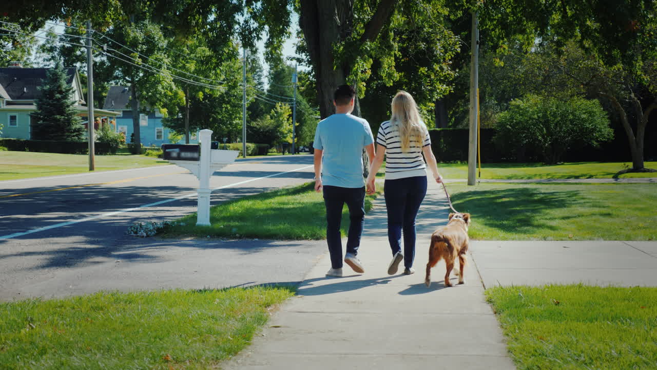 joven pareja multiétnica caminando por la calle con un perro
