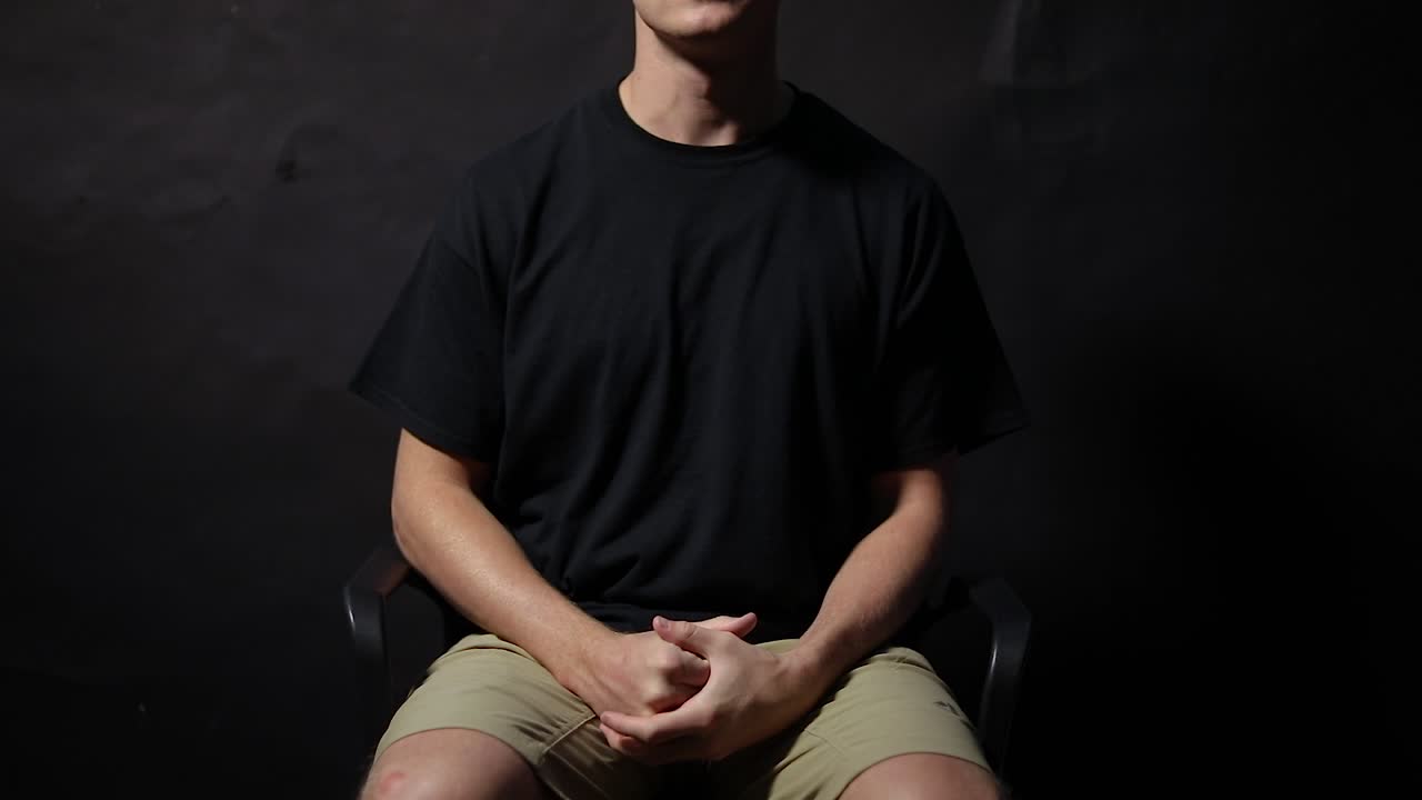 toma en cámara lenta de un hombre sentado en una silla jugueteando con las manos con ansiedad