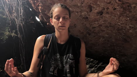 tilt finds woman meditating inside cave, then she stands up and leaves, brazil, slowmotion