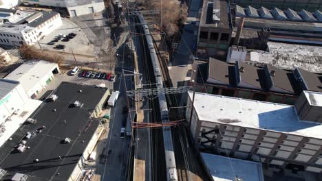 Amtrak-Acela-Partiendo-Pan-Up-Drone-Sobre-Pistas-Soleado-Día-De-Invierno-Estación-Wilmington-Delaware-Biden