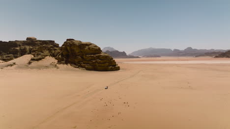 distant view of pick-up vehicle driving in arid desert of wadi rum in jordan