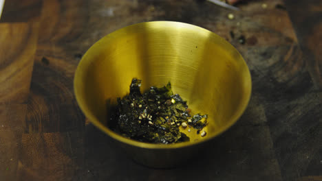 close up of chef putting fresh cutting seaweed into golden bowl,slow motion