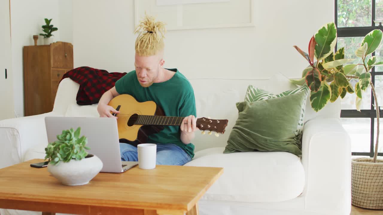 Albino african american man with dreadlocks playing guitars and singing