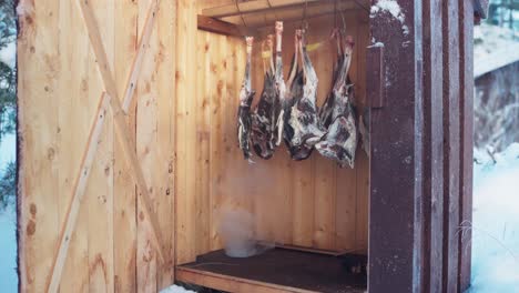 roe deer meat hanging inside smokehouse for traditional cold smoking in winter