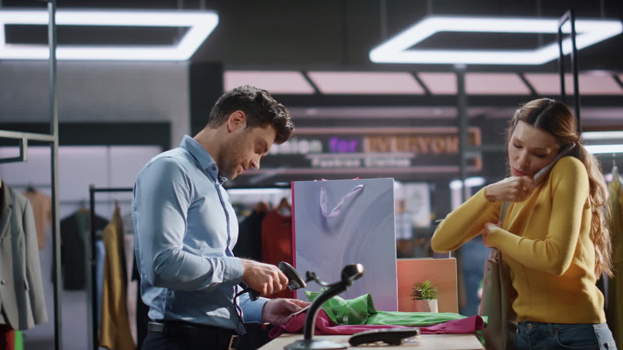 una mujer feliz compra ropa en el mostrador de caja. asistente escaneando artículos.