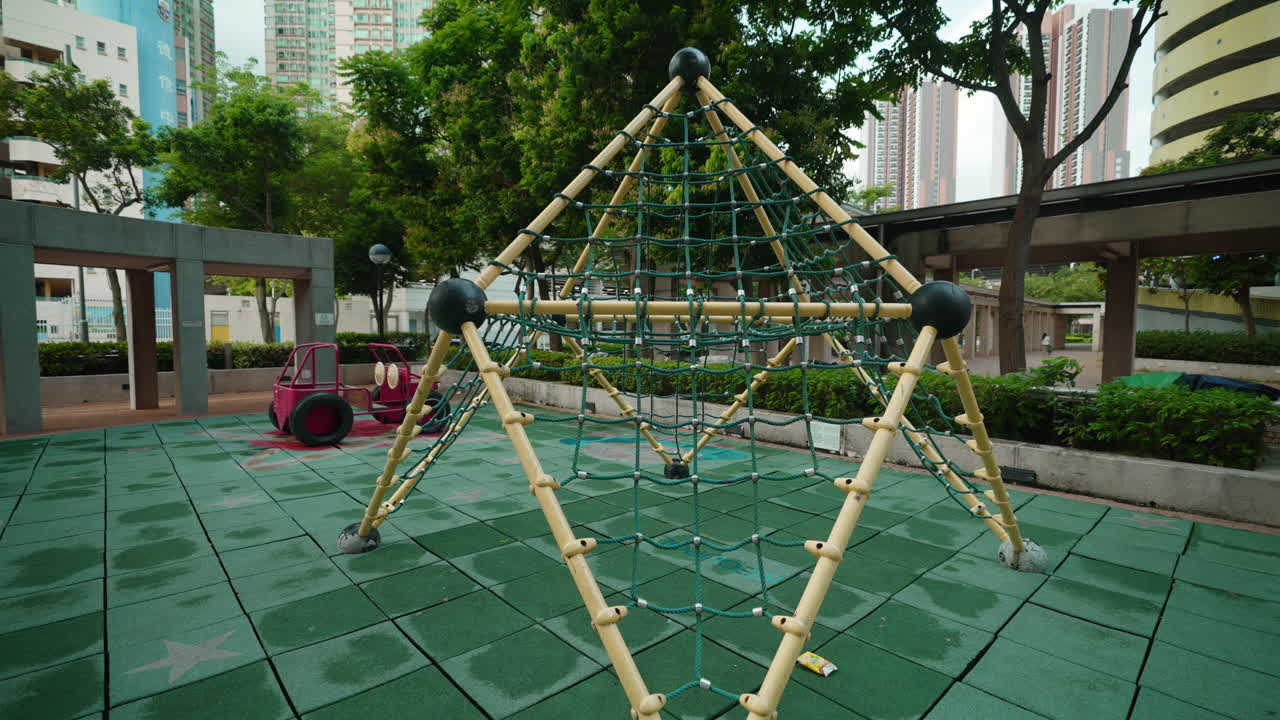 건물 과 초록색 나무 로 둘러싸인 게시물 을 가진 놀이터 의 영화적 인 공중 pull-back  ⁇