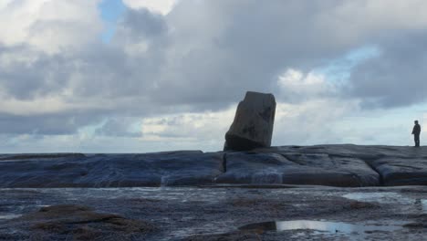 a man walks on the rocks close to the blowhole but manages to avoid getting wet