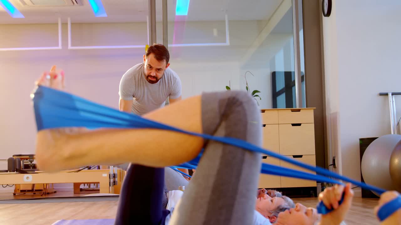 Træner hjælper ældre kvinder med at udføre yoga 4k