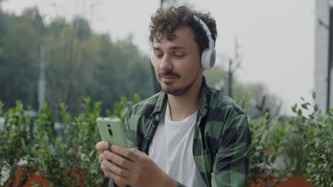 young man listening to music and using a smartphone outdoors