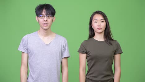 young asian couple pointing up