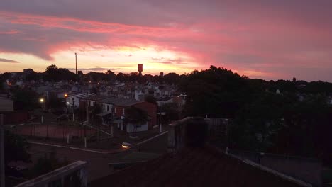 Vista-Aérea-De-Lento-Aumento-De-Los-Tonos-Rosados-Y-Dorados-De-Una-Puesta-De-Sol-Sobre-Villa-Cabello,-Provincia-De-Posadas,-Argentina