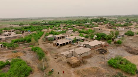 aerial pan shot of rural low rise buildings at village with dusty background