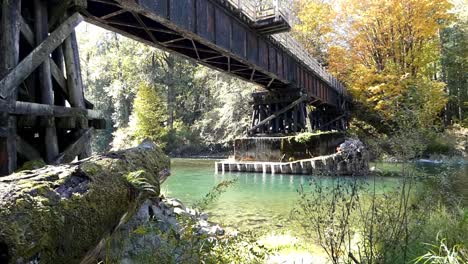 pov walking in forest to river with a trestle in background