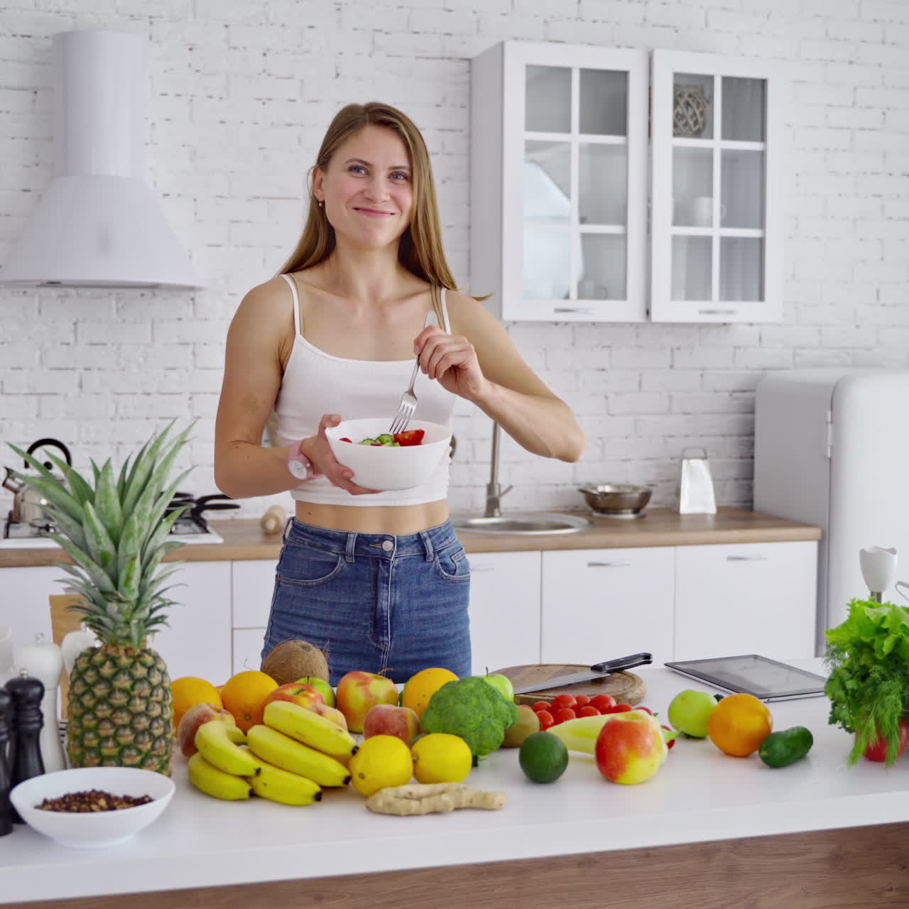 Woman with fresh salad in the kitchen. Attractive girl eating organic food at home. Beautiful housewife cooking salad. Healthy lifestyle.