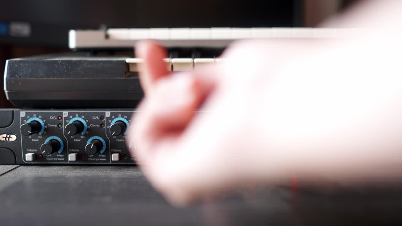 Close up view of the hand of a musician setting up audio levels in an audio mixer console.