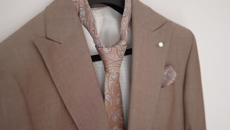 close up of elegant beige suit with paisley tie and matching pocket square detail