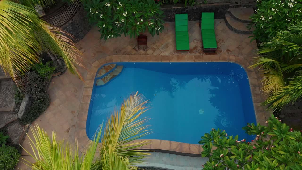 Luftfoto af fredfyldt resort poolområde med palmetræer i Amed, Bali, Indonesien
