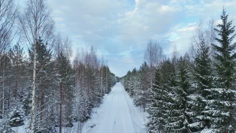 Drone-flight-over-a-road-with-snow-through-the-forest