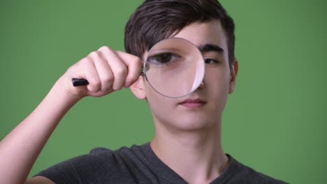 young handsome iranian teenage boy against green background