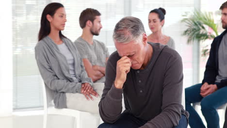 un hombre consola a otro en un grupo de rehabilitación en terapia.