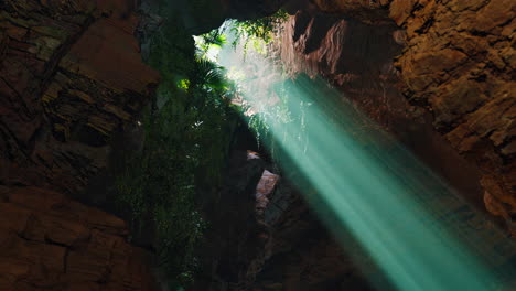 sunbeams shine through a hole in a cave roof