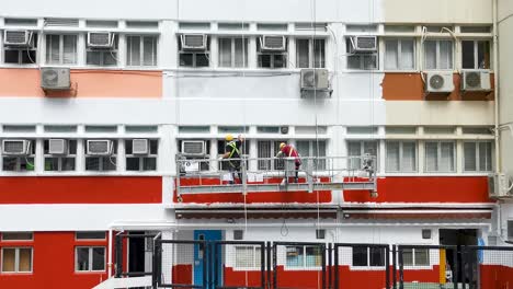 maintenance of the exterior wall of school building, two workers are painting on the wall, wong chuk hang, hong kong