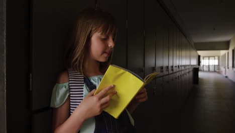 Girl-reading-books-in-the-school-corridor