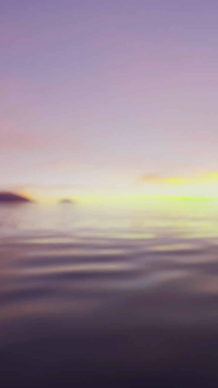 Sunset over calm water with distant hills on the horizon