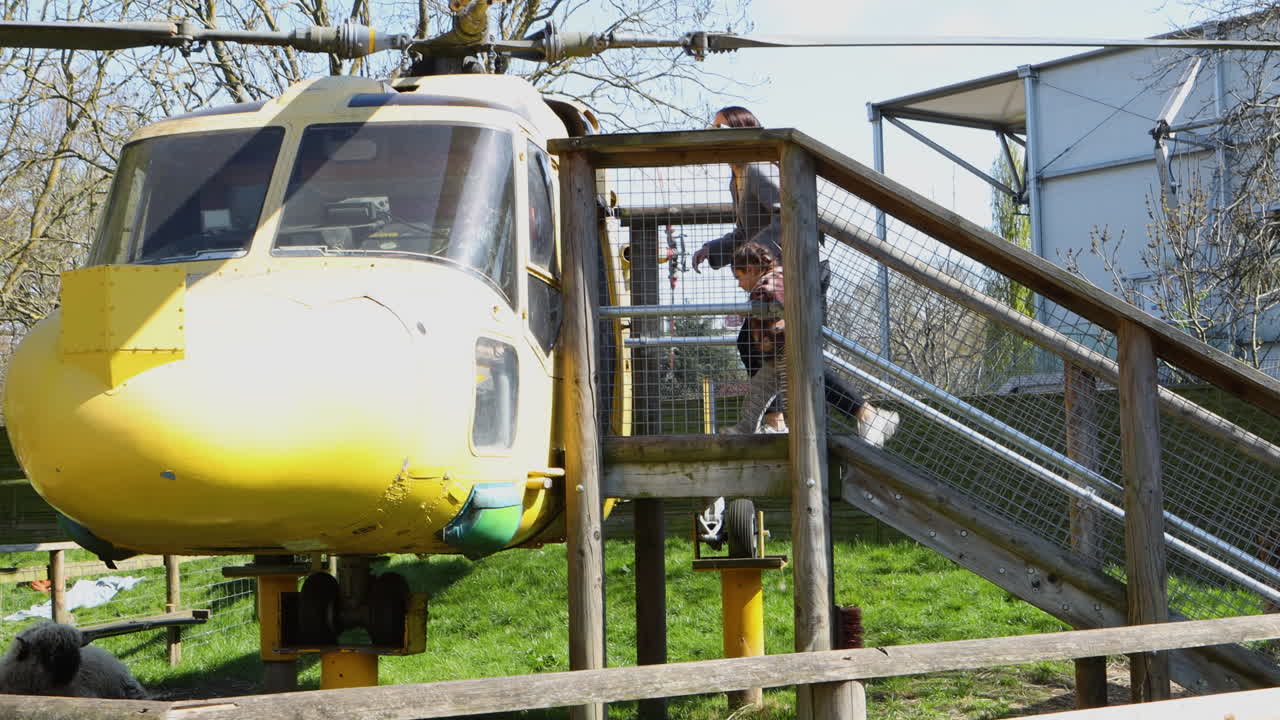 Helicopter exhibit in zoo, child and woman explore playfully on a sunny spring day