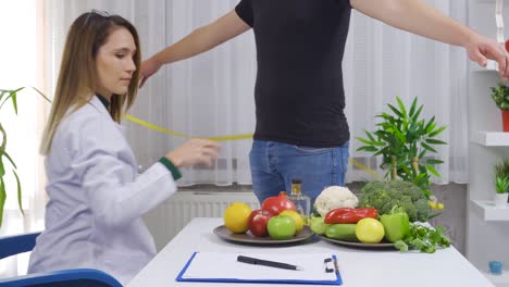 dietitian examining female patient, measuring her body with a tape measure.