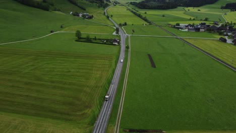 Alpine-Serenity:-4K-Aerial-Drone-Shot-of-Foggy-Drive-from-Graz-to-Hallstatt,-Cars-Wind-Through-Austrian-Countryside-with-perfectly-mowed-green-fields-and-Breathtaking-Alps-Panorama