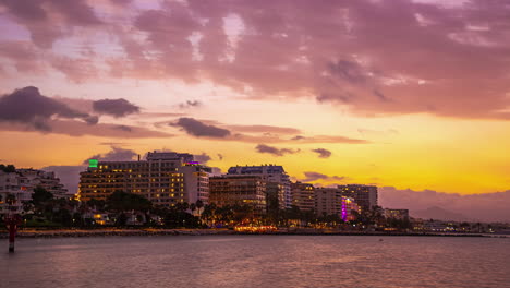 Twilight-descends-on-Malaga's-skyline-with-glowing-lights-reflecting-on-the-sea,-timelapse