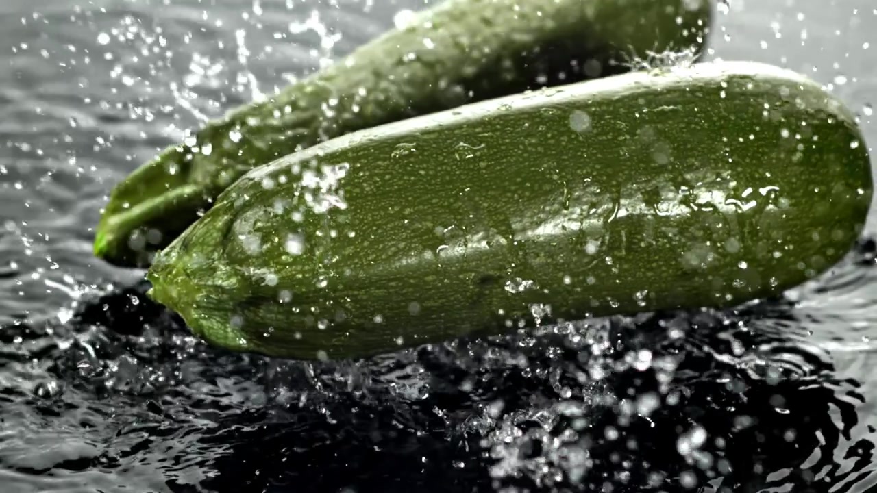 Gocce d'acqua che schizzano su zucchine verdi fresche.
