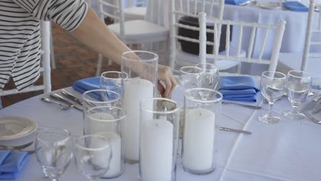 una mujer prepara la mesa en una recepción de boda elegante.