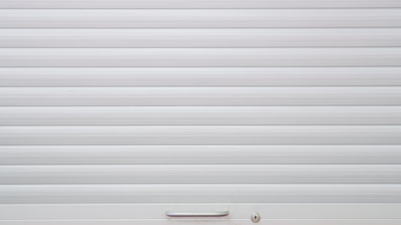 整備士が壁にある工具キャビネットのロールアップ ドアを開ける