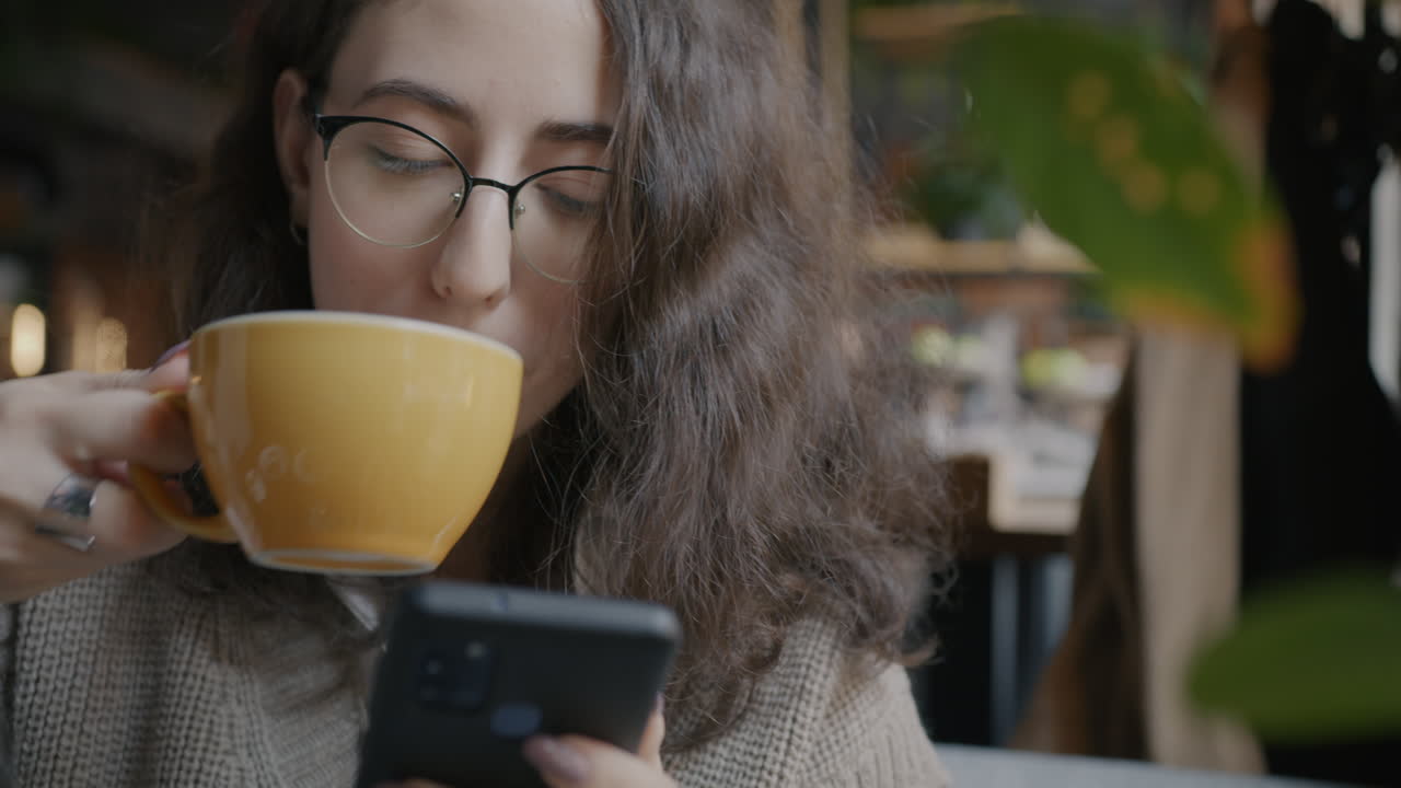 mujer usando un teléfono inteligente y bebiendo café en una cafetería