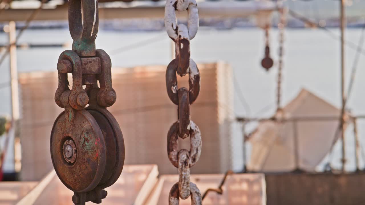 Pulley chains and rope hoist hang over deck of a fishing trawler.