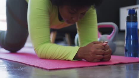 mujer afroamericana de tamaño grande acostada en un tapete de ejercicio haciendo ejercicio