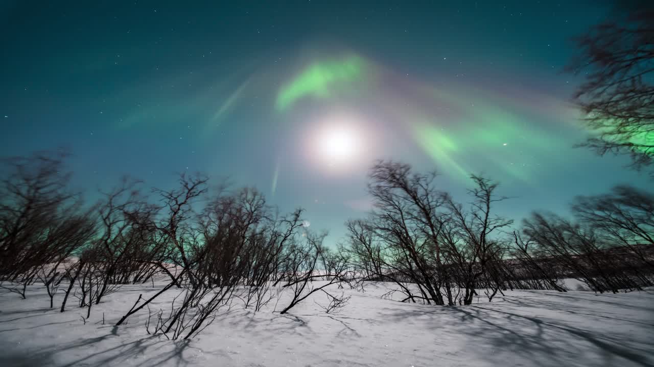 Snowy Arctic landscape with aurora borealis dancing over Kilpisjärvi in a timelapse