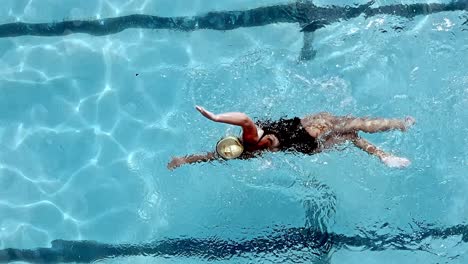 athletic woman swimming freestyle in a pool - overhead tracking view in slow motion