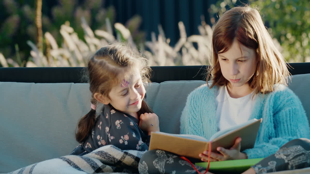 niños lindos leyendo un libro, relajándose en un columpio de jardín en el patio trasero de la casa