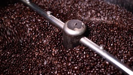 freshly roasted dark and oily coffee bins are mixed and cooled after coming out of the roaster in a local coffee shop