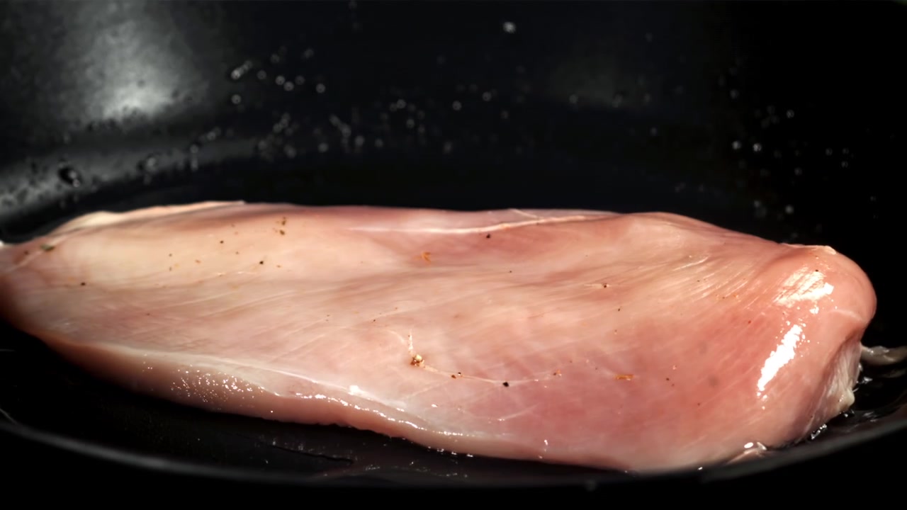Raw Chicken Breast Sizzling in a Hot Frying Pan