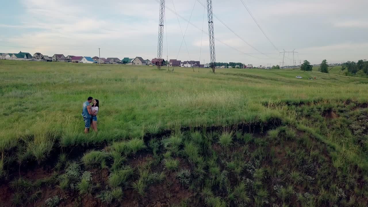 에어리얼 뷰 젠 ⁇  베스트를 입은 남자가 갈색 여자를 포옹하고 키스합니다.