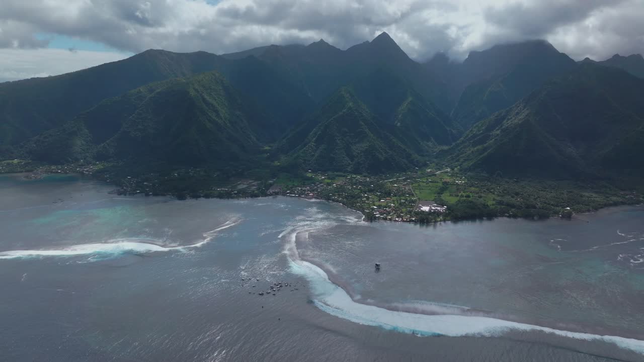 Coastal Teahupoo Tahiti aerial drone view perspective French Polynesia coral reef surf break waves mountains Pacific Ocean channel boats cloudy sunny daytime Point Faremahora Pass Havae forward motion
