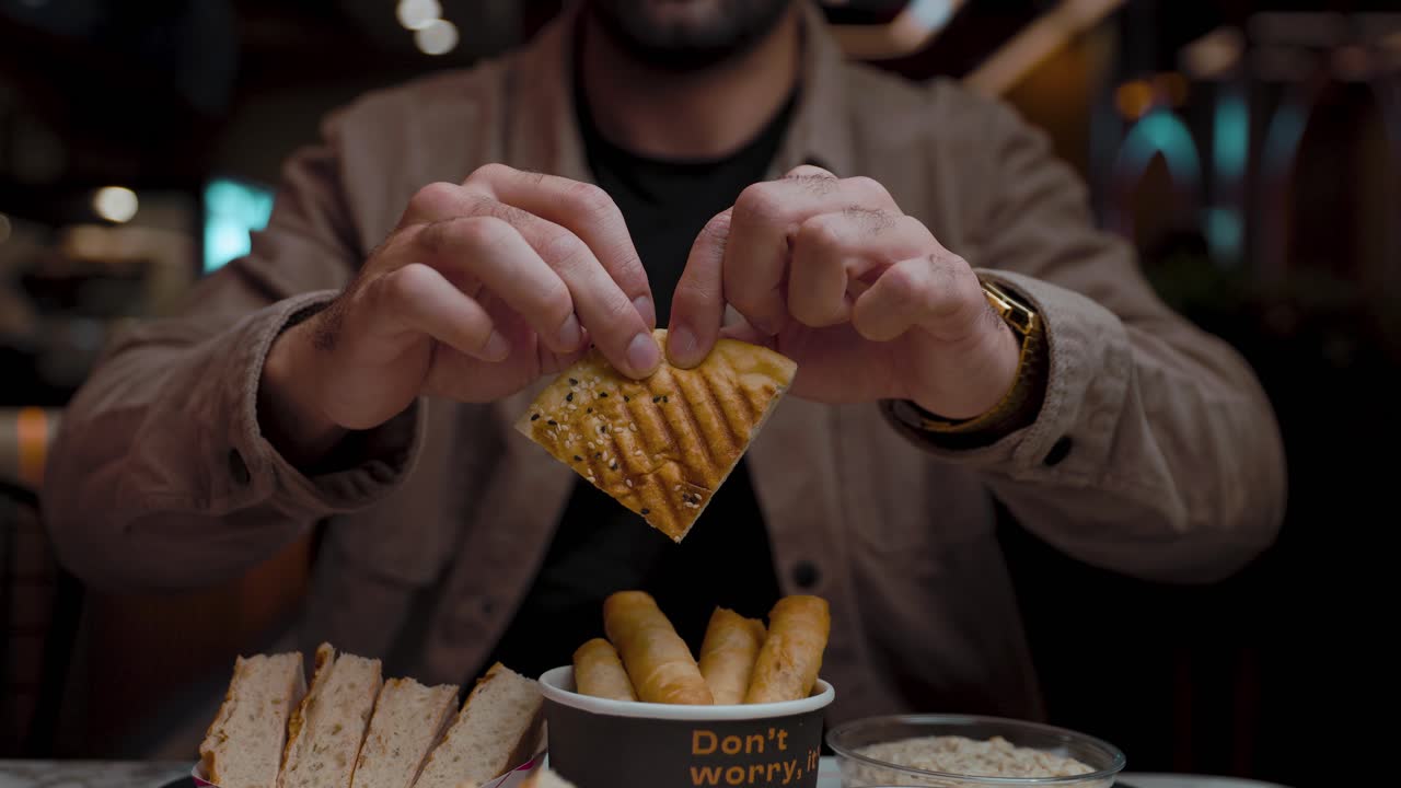 Close up of a Man Ripping a Piece of Bread in Half at a Restaurant